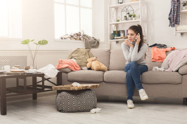istock Desperate woman sitting on sofa in messy room 953084198
