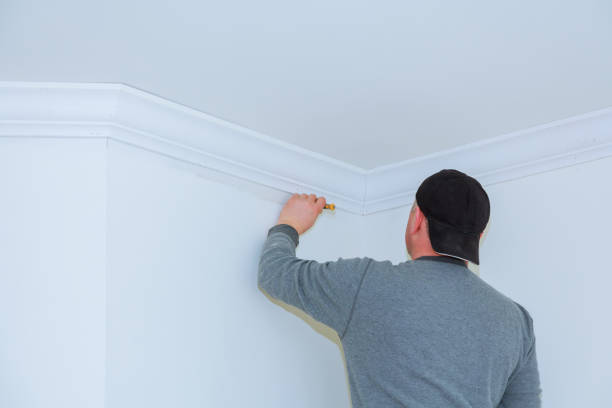 istock Installation of ceiling moldings. Worker fixes the wood molding to the ceiling 953090668