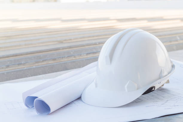 istock The white safety helmet put on the blueprint at construction site 953108692