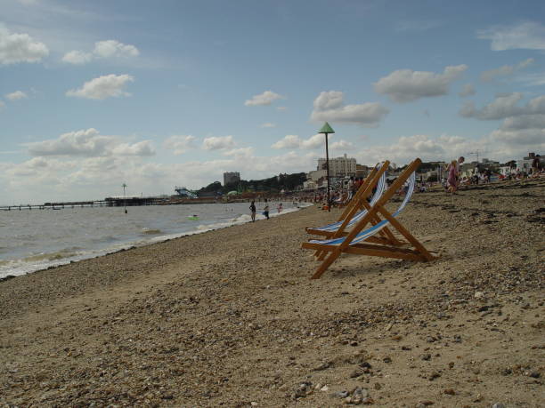 View on beach at Southend-on-Sea, UK on one summer day: sun loungers, people of different ages. Seafront, blue sky.