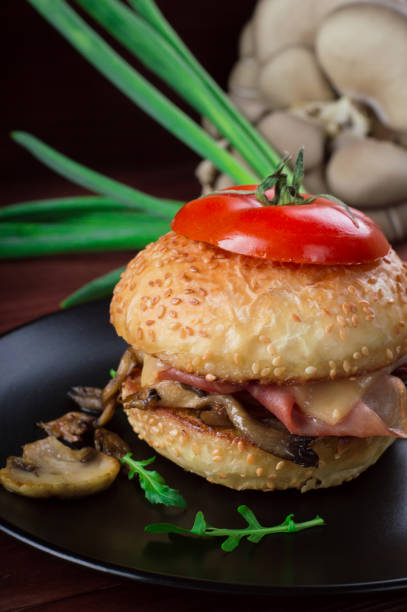 istock Burger with fried mushrooms, ham, onions and cheese on rustic background 953138532