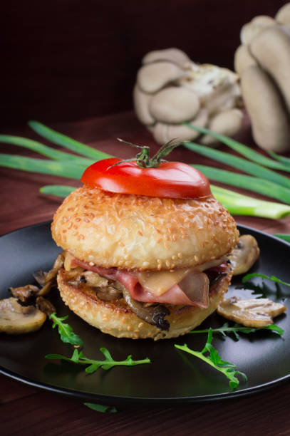 istock Burger with fried mushrooms, ham, onions and cheese on rustic background 953138624