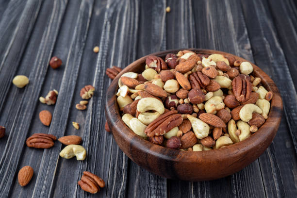 istock Nuts mix Almonds, Cashews, Macadamia, Peanuts, Walnuts, Pecans, Pine Nuts, Pistachios in a wooden plate. 953148424
