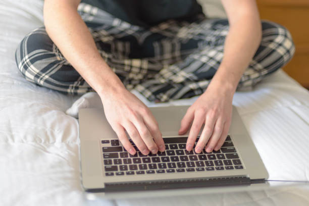 istock Low Section Of Man Using Laptop On Bed At Home 953148888