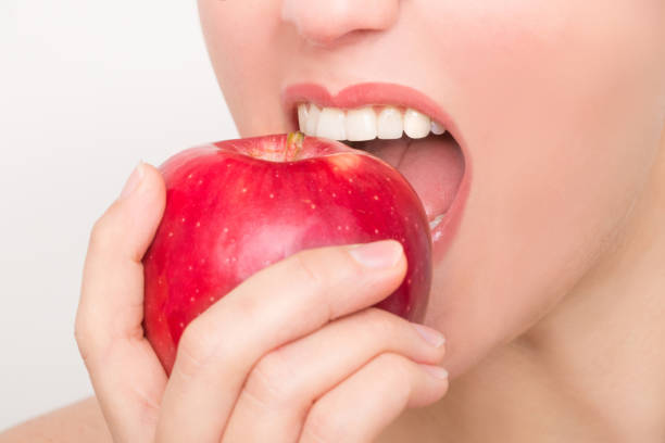 istock Beautiful female mouth with white teeth bites into a red apple 953152442