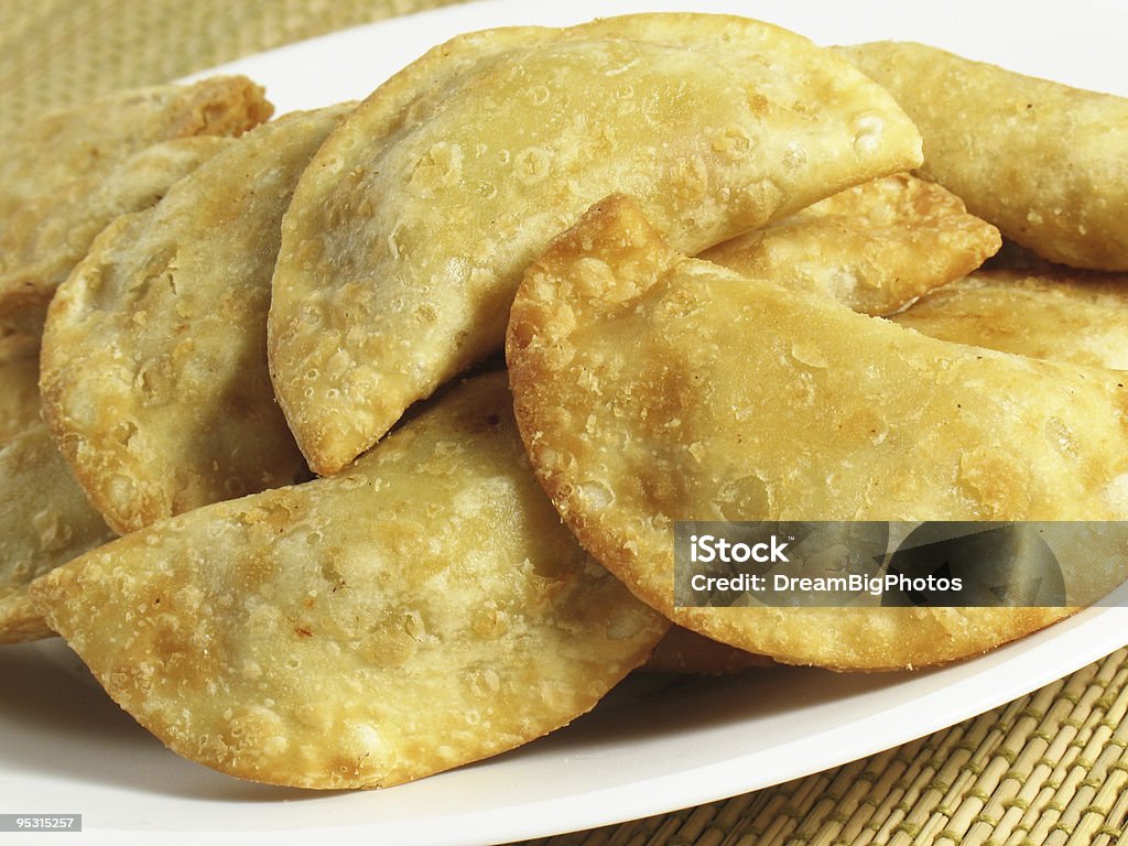 Crispy empanadas on a white plate A fried pastry filled with meat, spices, and cheese. Empanada Stock Photo