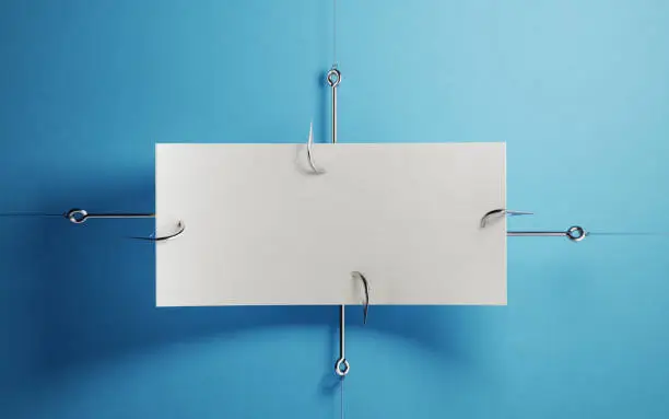 Blank white paper hooked by fishing hooks over blue background.  Phishing concept. Horizontal composition with copy space.