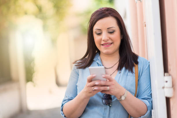 istock Pretty young woman using her mobile phone in the street, light effect 953160166