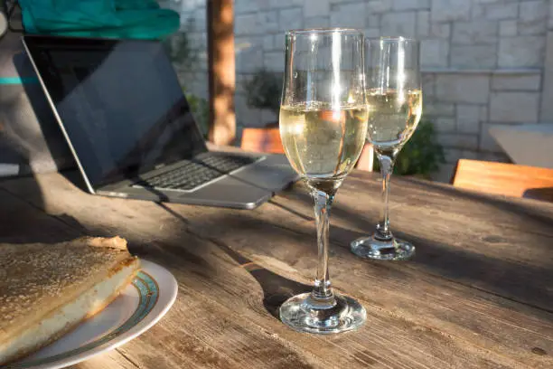 Glasses of sparkled white wine on dining table with laptop, Crete, Greece