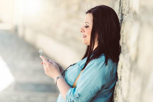 istock Pretty young woman using her mobile phone in the street, light effect 953160634