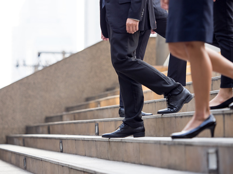 Close up legs of businessman and businesswoman in suit, walking down from stairs, go on business, go down, loss, retired, unemployment and quit from job concept