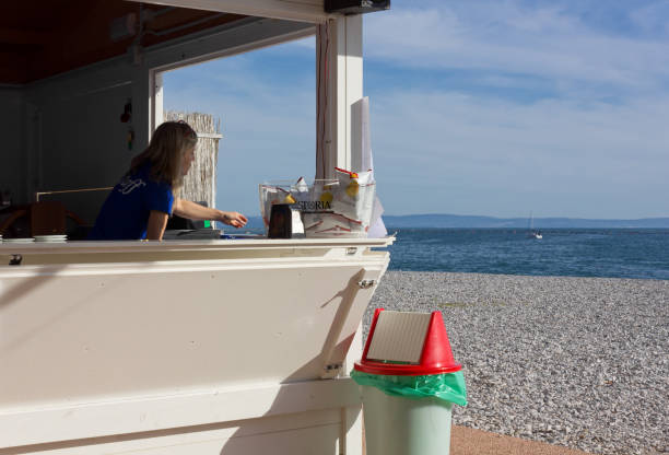 DUINO AURISINA, Italy - April 14, 2018: Blonde woman working at a beach bar in Sistiana seaside resort near Trieste
