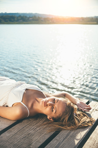 Beautiful young woman enjoying sunset at the lake