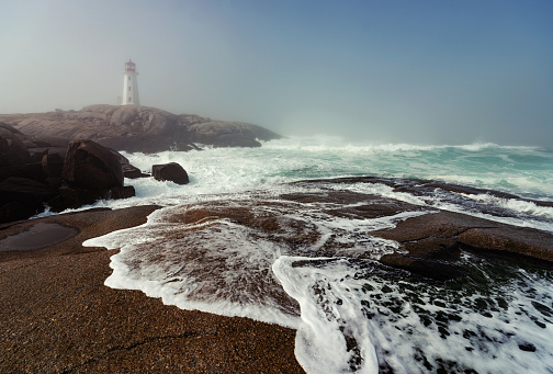 Peggy's Cove Lighthouse in early morning light and fog.