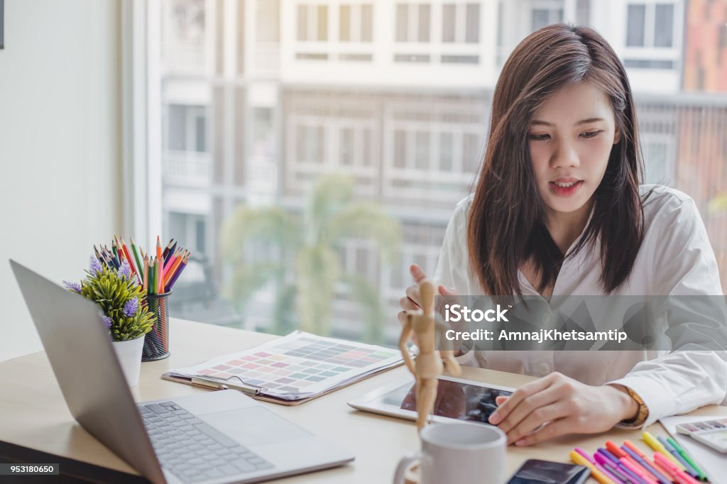 Young woman graphic designer working on laptop and computer in the office Graphic Designer Stock Photo