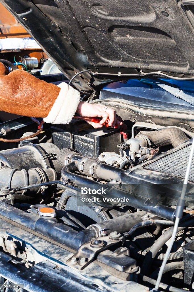 Jumpstart a dead car battery with another vehicle Jumpstart a dead car battery with another vehicle and jumper leads in cold winter day Car Stock Photo