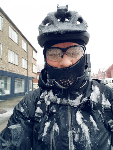 Commuter on bike is covered in snow and ice on the way to work Man with bicycle helmet is taking a selfie. He is covered in snow while being on the way to road on his bike. He wears head wear and protective glasses. frost face stock pictures, royalty-free photos & images