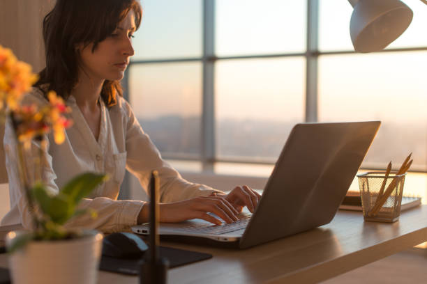 istock Side view photo of a female programmer using laptop, working, typing, surfing the internet at workplace. 953193506