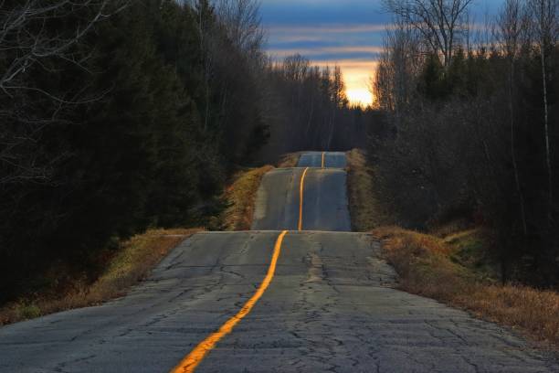 Sunset light on bumpy country road Rural scene of old road over hills at sunset bumpy stock pictures, royalty-free photos & images