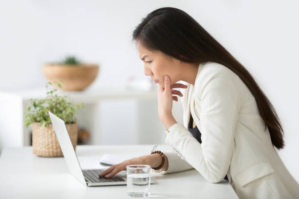 istock Puzzled confused asian woman thinking hard looking at laptop screen 953210686