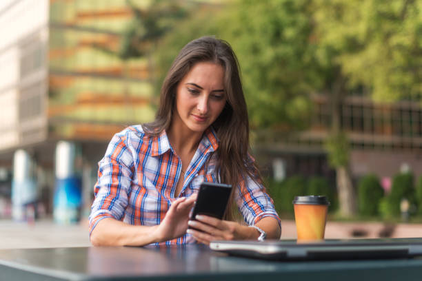 istock Attractive young woman reading a text message on her cell phone. Girl sitting outdoors using smartphone 953218698