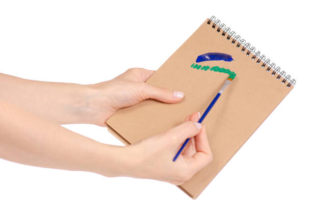 istock Notepad for drawing and brush with paint in hand 953226232