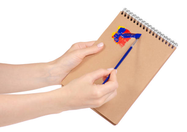 istock Notepad for drawing and brush with paint in hand 953226360