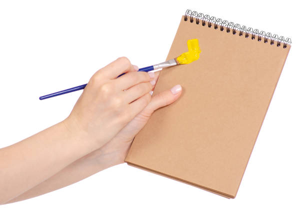 istock Notepad for drawing and brush with paint in hand 953226556