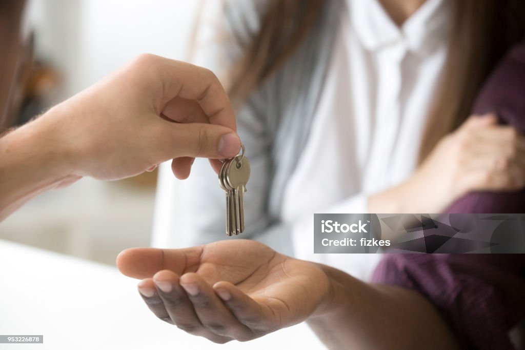 Real Estate Agent giving african customer keys, couple buying new house, closeup Real Estate Agent giving african customer taking keys to new home, interracial couple clients buying rental house, mortgage loan investment, real estate deal or property ownership concept, hands close up view Giving Stock Photo