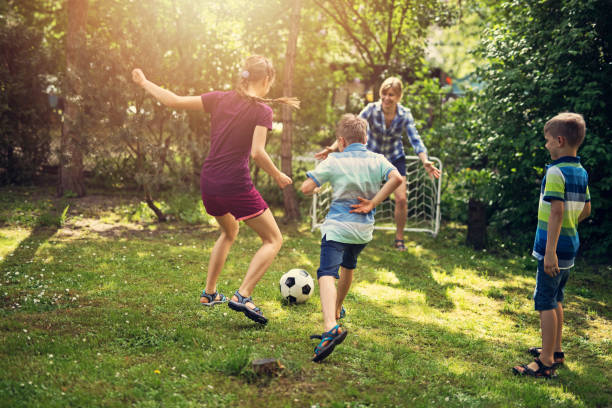 família se divertindo jogando futebol no jardim - action family mother sport - fotografias e filmes do acervo