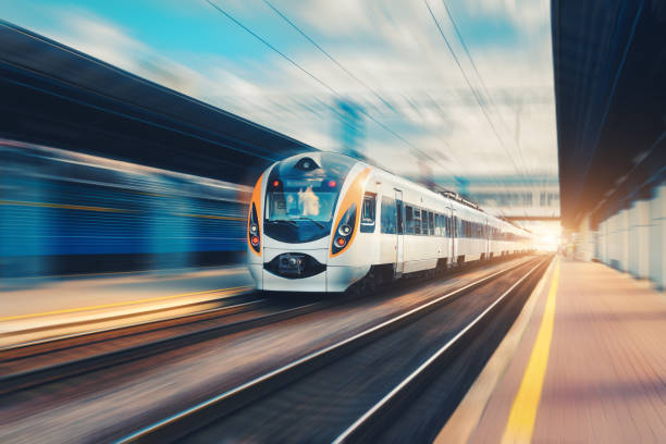 ヨーロッパで夕暮れ時の駅上のモーションの速度旅客列車。鉄道プラットフォーム モーション ブラー エフェクトを使ってモダンな都市間の列車。鉄道と都市のシーン。鉄道輸送 - business speed horizontal commercial land vehicle ストックフォトと画像