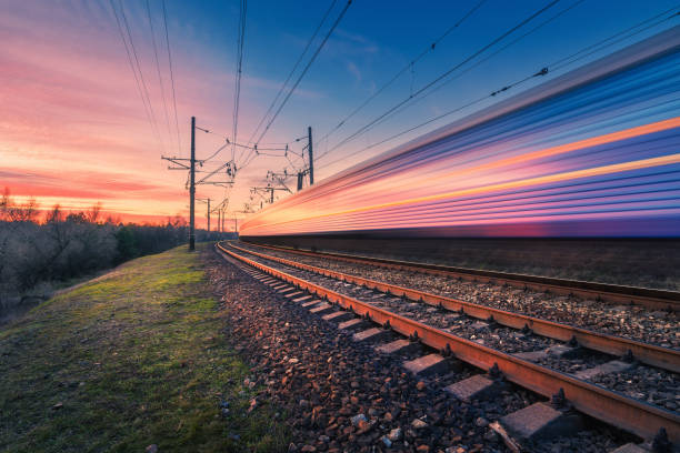 High speed passenger train in motion on railroad at sunset. Blurred modern commuter train. Railway station and colorful sky. Railroad travel, railway tourism. Industrial landscape. Transportation High speed passenger train in motion on railroad at sunset. Blurred modern commuter train. Railway station and colorful sky. Railroad travel, railway tourism. Industrial landscape. Transportation rail transportation stock pictures, royalty-free photos & images