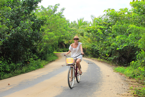 Young beautiful tourist riding a bike in the sand roads of Bocas del Toro islands in Panamá.