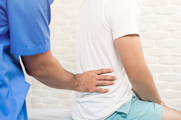 male doctor therapist treating lower back pain patient in clinic - reflexology massaging recovery sport imagens e fotografias de stock