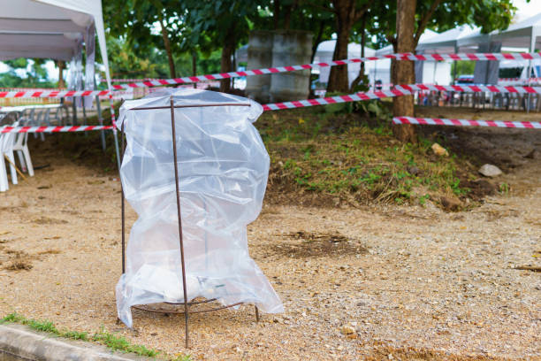 istock big transparent trash bag hanging on rusty steel structure for security policy to see if terrorist put bomb in it with Red and white tripped tape fence for barricades or murder zones or crime scene. 953267856