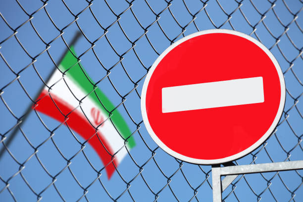 флаг ирана за забором с табличкой запрещен - iran стоковые фото и изображения