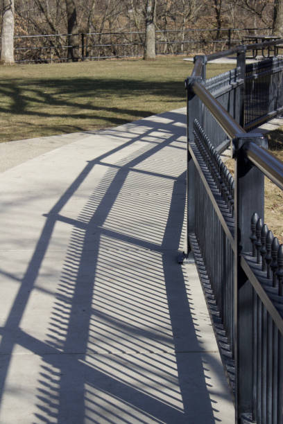 The shadows of people and railings are reflected on the stone slab