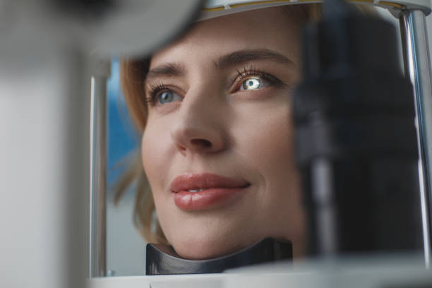 Glad female examining eyesight with equipment