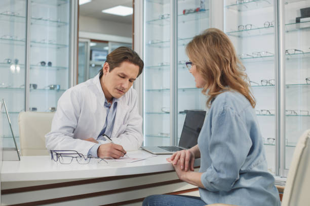 Focused ophthalmologist telling with female visitor