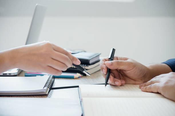 istock Young students campus or classmates with helps friend studying for a test an exam in workbook learning in classroom, Tutor books with friends, Education school concept 953272802