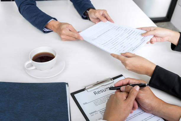 Interviewer or Board reading a resume during a job interview, Employer interviewing a young male job seeker for recruitment talking in modern office, employment and recruitment concept. entrevistador o tablero leyendo un curriculum vitae durante una entrevista de trabajo, empleador entrevistando a demandante de empleo joven masculino para hablar en la oficina moderna, el empleo y el concepto de reclutamiento de reclutamiento