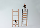 Wooden ladders and miniature people. The concept of gender inequality in promotion.