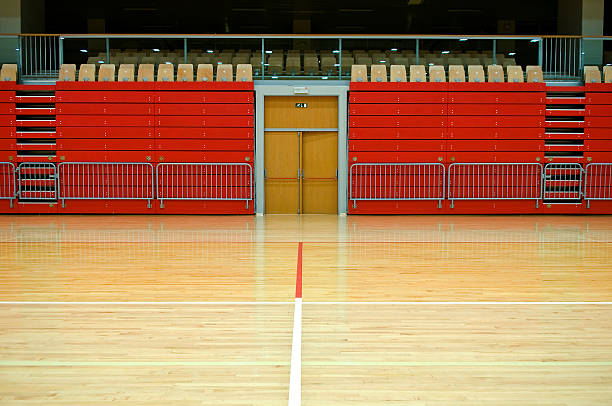Sports hall with red stand, door in the middle, seats, parquet with red and white lines.