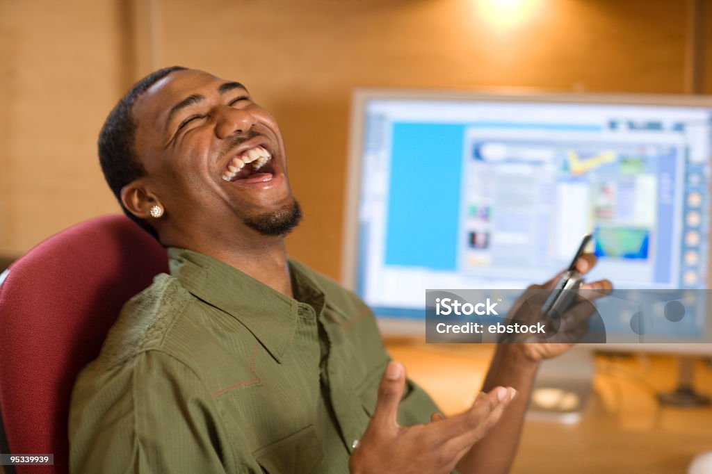 Śmiać się Młody człowiek z telefonu komórkowego i komputera - Zbiór zdjęć royalty-free (Afrykanin)