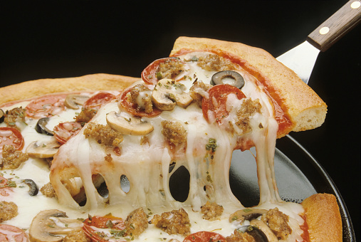 A slice of pizza is lifted from the pan with a spatula