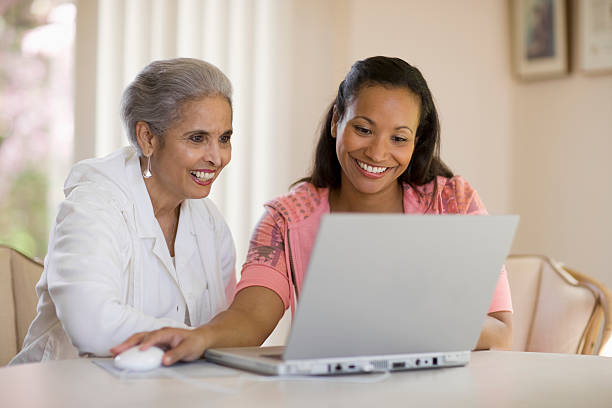 mère et fille partagent un ordinateur - women togetherness teaching laptop photos et images de collection