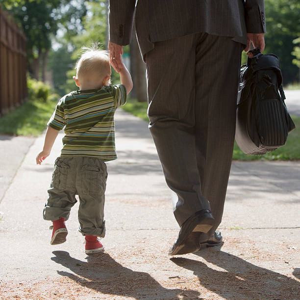 Working Dad walking with son stock photo