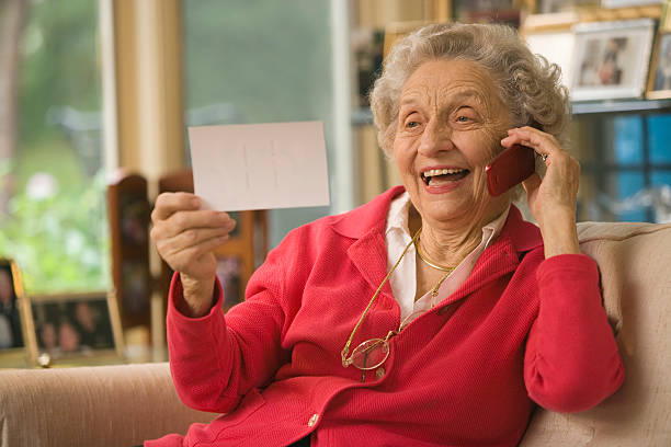 Senior looking at photograph and talking on cell phone stock photo