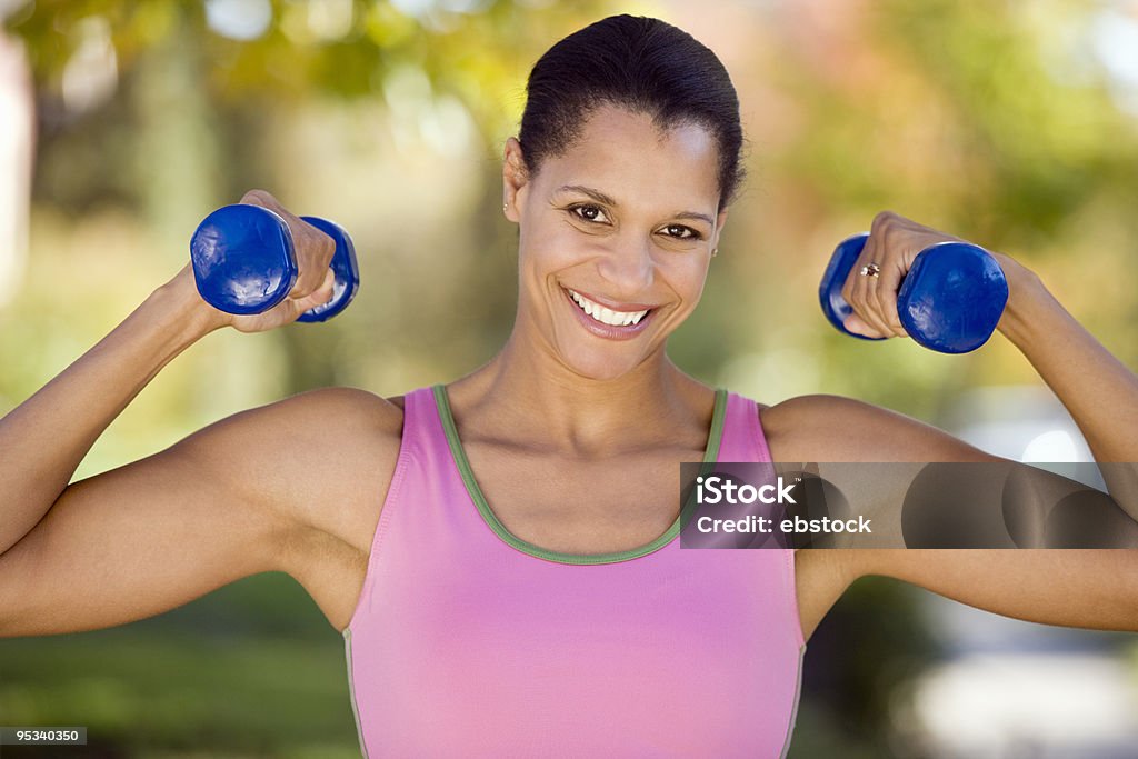 A woman lifting weights happy to be working out Pretty African American woman working out Adult Stock Photo