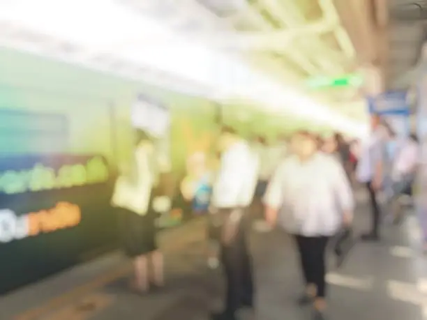 Photo of Abstract blurred image of people  standing in lines waiting for train coming and using mobile phone in electric sky train station in Thailand.